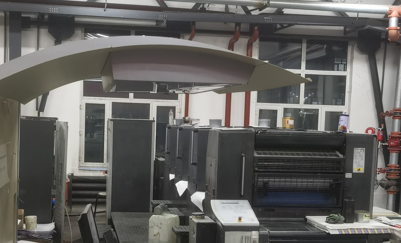 Real workshop photo: multicolor offset press first unit and feeding console where lay and detector status are monitored